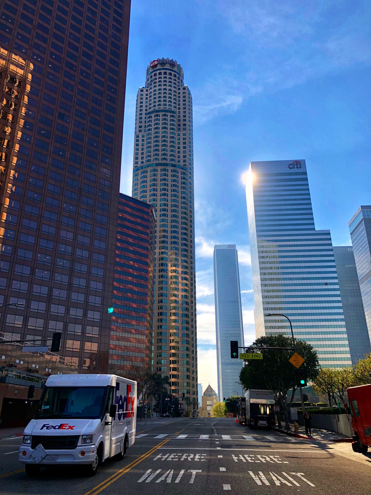 A delivery van at an empty crossing, with a rounded tower and the light between the buildings