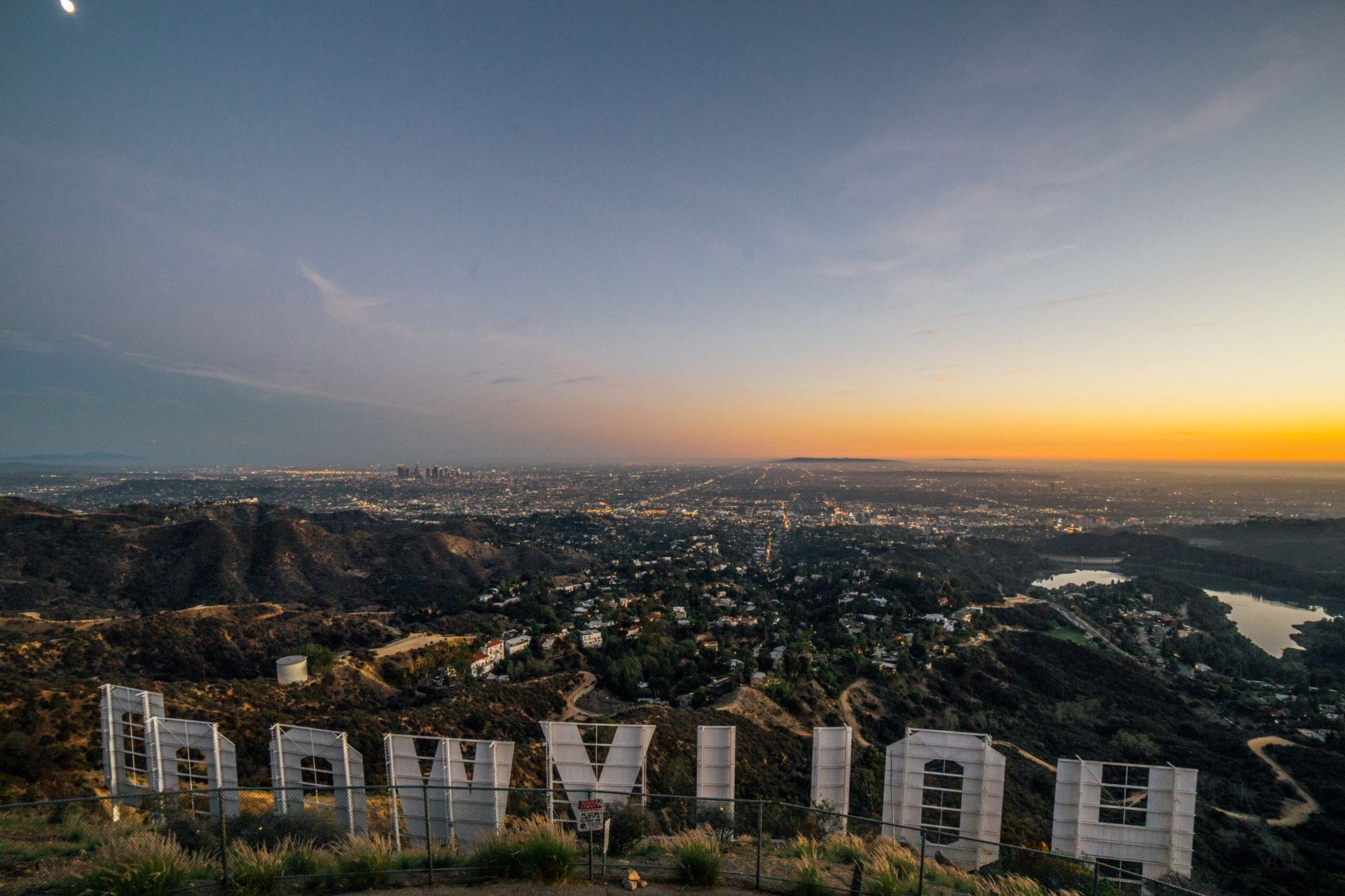 The back of the Hollywood Sign at dusk, with the lights of Los Angeles stretching to the horizon